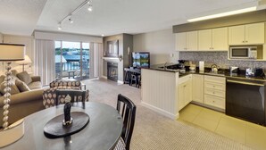 A modern living room with a dining area, kitchen, and a fireplace. - Edgewater 229 | Relaxing Condo in Downtown Charlevoix | Pool, Hot Tub, Sauna (Charlevoix)