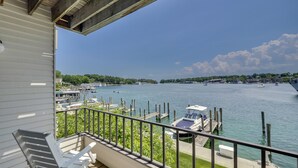 A balcony with a view of a marina, boats, and a distant shoreline. - Edgewater 229 | Relaxing Condo in Downtown Charlevoix | Pool, Hot Tub, Sauna (Charlevoix)