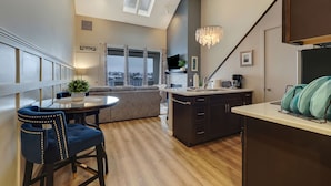 A modern kitchen with a dining area, a chandelier, and a view of the city. - 345 Edgewater | 2BR Stay | Downtown Charlevoix | Pool, Hot Tub, Sauna (Charlevoix)