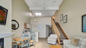 A living room with a sofa, a wooden table, and a dining area with chairs. - 347 Edgewater | 3rd Floor Balcony | Downtown Chx | Pool, Hot Tub, Sauna (Charlevoix)