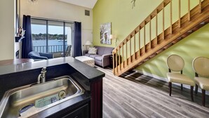 Un salon moderne avec un coin cuisine, un escalier et une vue sur la mer.