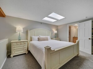 A bedroom with a bed, two nightstands, a dresser, and a door. - Edgewater 357 | Downtown Charlevoix | Pool, Hot Tub, Sauna (Charlevoix)
