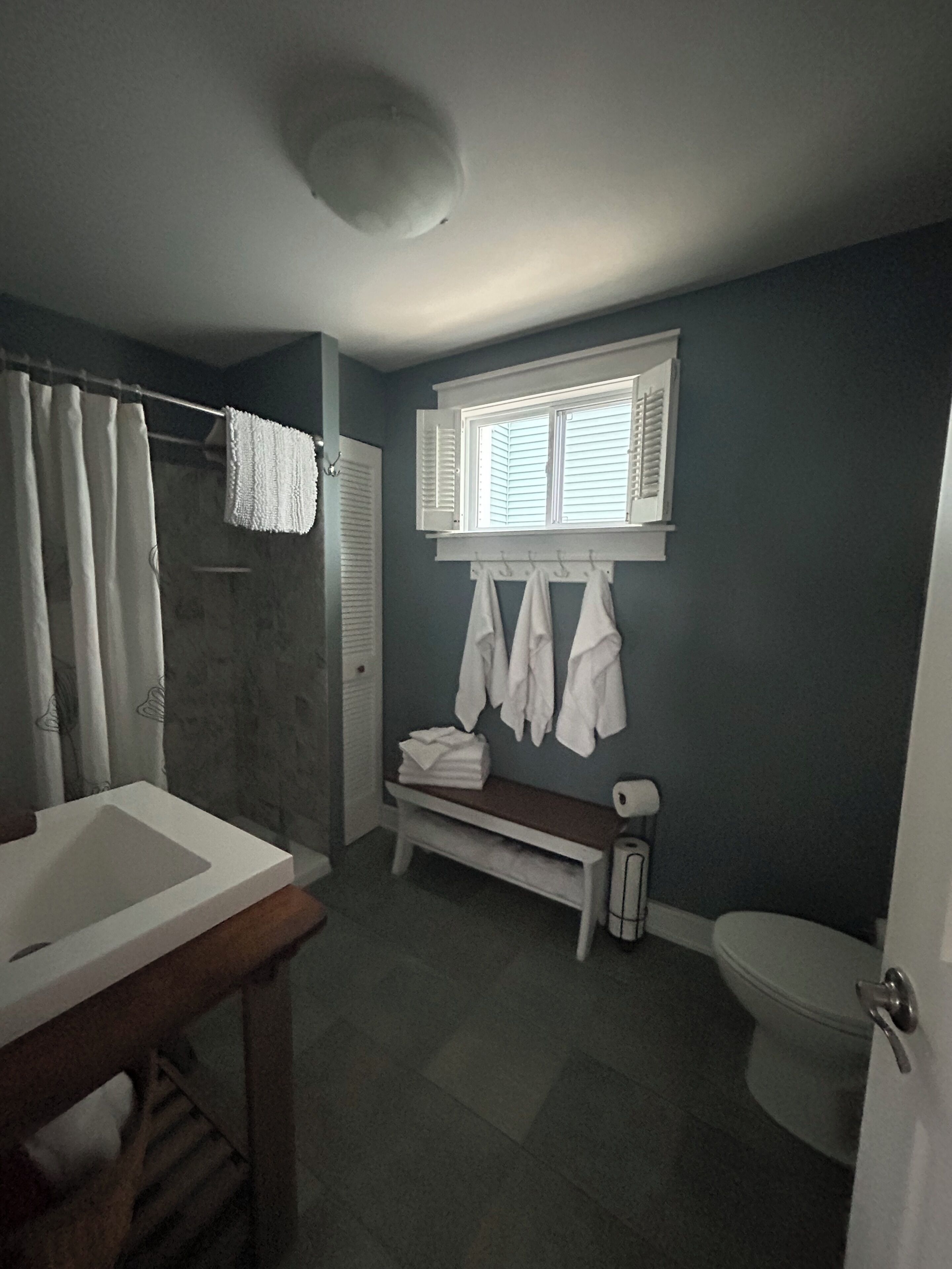 Une salle de bain équipée d’une douche, d’un lavabo, de toilettes et d’une fenêtre avec des stores.