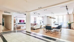 A spacious living area with a large dining table, sofas, and a kitchen in the background. - YOUR SOLUTION TO A LUXURY STAY- 250M2 TOP LUXURY CHAMPS ELYSEES (Paris)