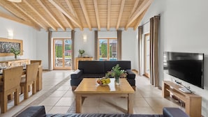 A spacious living area with a wooden ceiling, a black sofa, a wooden coffee table with fruit, a TV, and a dining area with wooden furniture. - Villa Bonassini with whirlpool, sauna and 4 bedrooms  (Svetvinčenat)
