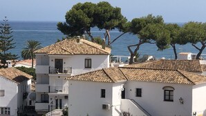 A coastal building with a tiled roof and white walls, overlooking the sea.