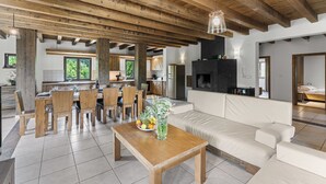 A spacious living area with a wooden dining table, a sofa, and a kitchen in the background.