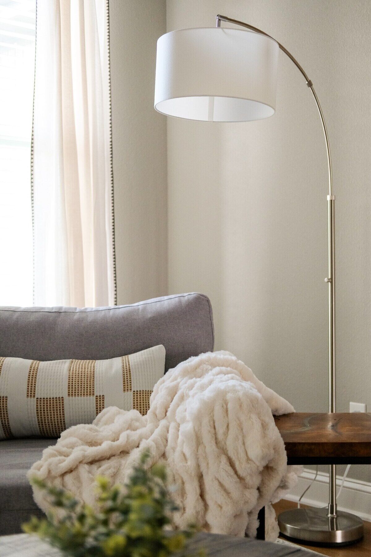 A modern living room with a grey sofa, a white throw blanket, and a floor lamp.