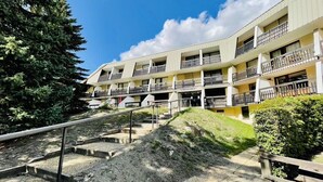 Un hôtel à plusieurs étages doté de balcons, d’un escalier et d’une pelouse bien entretenue.