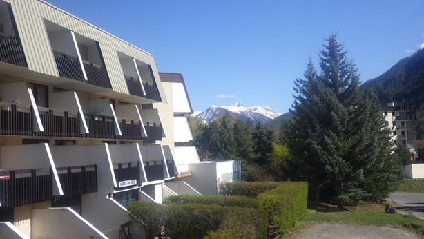 Un bâtiment moderne doté de balcons et offrant une vue sur des montagnes enneigées.