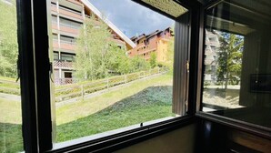 Une fenêtre donnant sur un immeuble doté de balcons et sur un espace verdoyant.