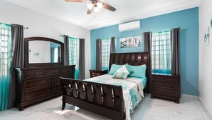 A bedroom with a bed, dark wooden dresser, and a ceiling fan. - Fortune Rise. Car Rental available  (Mount Fortune)