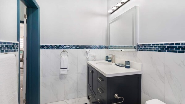 Een moderne badkamer met een witte wastafel, donkere kastjes en een blauwe betegelde spatwand.