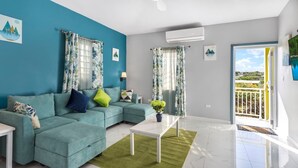 A living room with a teal sofa, a white coffee table, and a view of a balcony. - Fortune Rise. Car Rental available  (Mount Fortune)