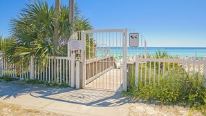 Une entrée de plage fermée par une barrière, avec un panneau indiquant qu’il s’agit d’une propriété privée et que l’accès est interdit.