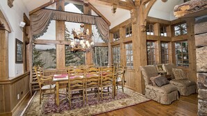 A rustic interior with a wooden dining area, a cozy seating area, and large windows offering a view of the outdoors. - 349 Holden Rd. 5 Bedroom Home by RedAwning (Avon)