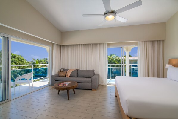 Ein Hotelzimmer mit Balkon, einer Couch, einem Bett und einem Deckenventilator.