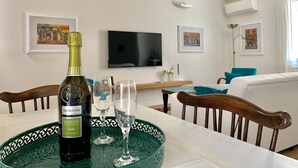 Uma área de refeições com uma mesa posta para dois, apresentando uma garrafa de vinho e copos.
