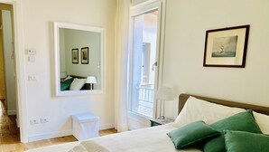 Un letto rifatto con cuscini verdi, una lampada da comodino e un quadro appeso al muro.