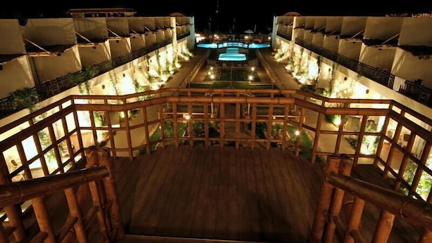 Un hotel con una escalera de madera que conduce a una zona de piscina, rodeada de varios balcones con luces.