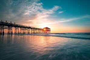 A pier extending into the ocean with a sunset in the background.