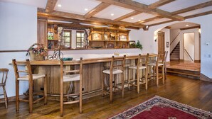 A rustic kitchen with a wooden bar and bar stools, a large window with curtains, and a staircase leading to another room. - Spectacular house on shuttle route, grand piano, pool table (Beaver Creek)