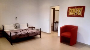 A bedroom with a bed, a chair, and a painting on the wall.