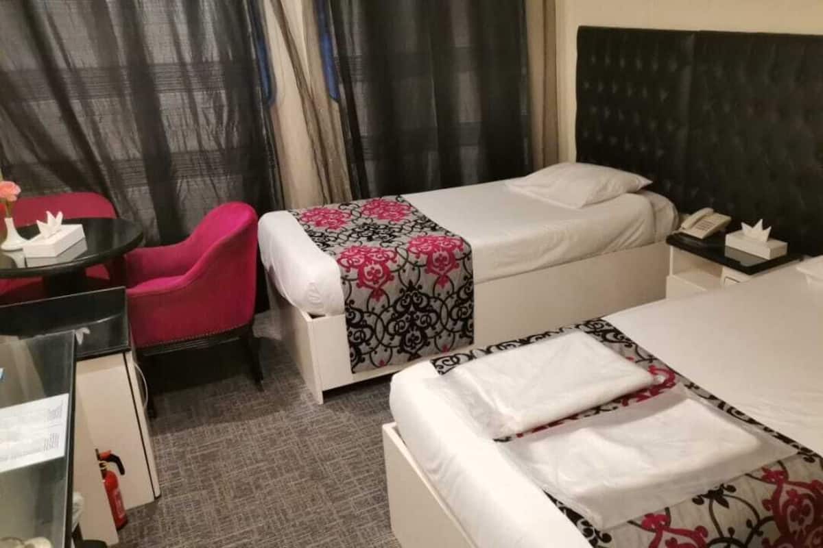 Ett hotellrum med två sängar, ett skrivbord, en stol och ett nattduksbord.