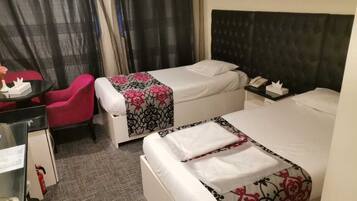 A hotel room with two beds, a desk, a chair, and a nightstand.