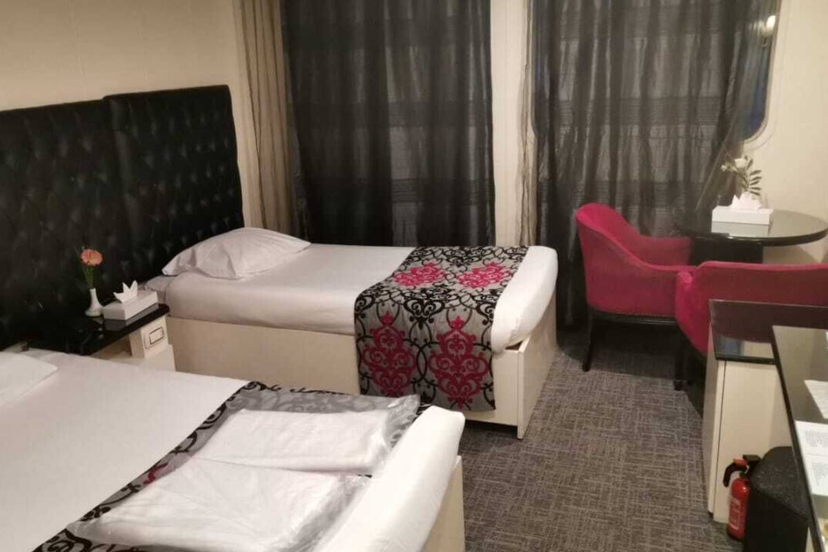 Ett hotellrum med två sängar, ett skrivbord, en stol och ett litet bord.