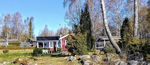 Cozy cabin nestled in a forested area with a well-maintained lawn and inviting porch.