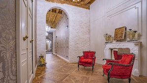 A hallway with wooden flooring, white walls, and two red chairs. - Corte Rubbi 6, Deluxe Studio Apartment (Venice)