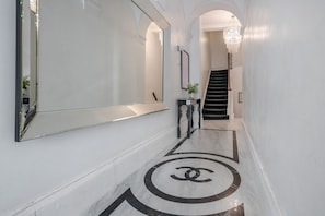 Stylish space with a large mirror, console table, and chandelier, set against a distinctive floor pattern.