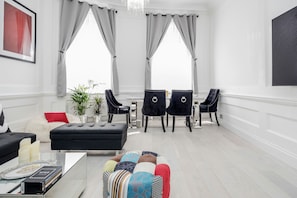 Relax in this stylish living room with a black sofa, colorful ottoman, and dining area.
