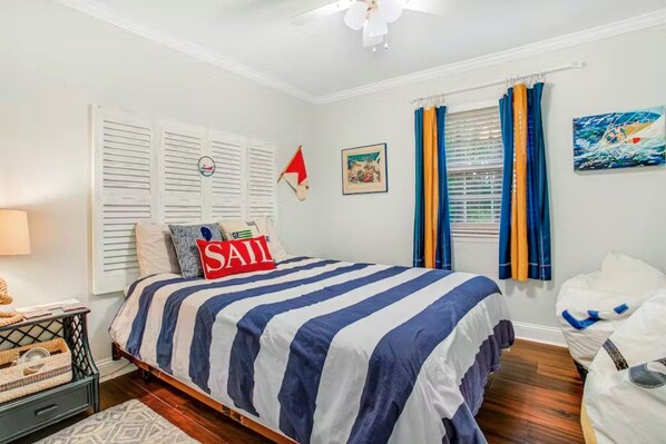 Une chambre à coucher avec un lit, une fenêtre avec des rideaux, une horloge murale et un tableau.