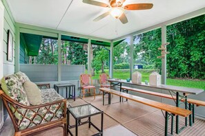 Une terrasse couverte avec un ventilateur de plafond, une table à manger, des chaises et un canapé.