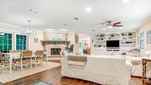 Un salón amplio con chimenea, un comedor con sillas, un sofá y un televisor en una cocina moderna.