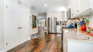 Una cocina con armarios blancos, un refrigerador de acero inoxidable y una encimera de granito.