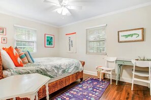 Une chambre à coucher avec un lit, un bureau, une chaise et une fenêtre avec des stores.