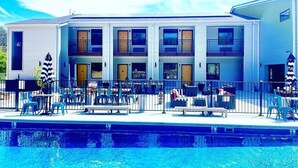 A multi-story building with a swimming pool in front. - Family staycation suite near Six Flags in The Landing Hub Hotel with onsite activities (Pacific)