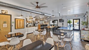 Ein modernes Restaurant mit hohen Decken, freiliegenden Lüftungsrohren und einer Mischung aus schwarzen und weißen Tischen und Stühlen.