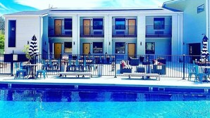 Ein modernes Gebäude mit Schwimmbad, Außenbereich zum Sitzen und einem eingezäunten Patio.
