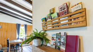 Une étagère en bois avec des guides de voyage et une fougère en pot.