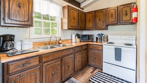 Une cuisine avec des meubles de rangement en bois, une cuisinière, un four à micro-ondes et une machine à café.