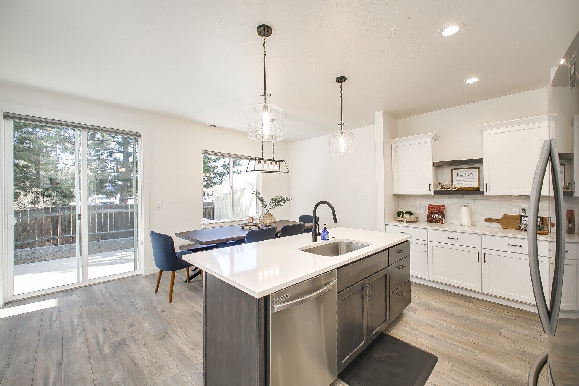 A modern kitchen with a central island, stainless steel appliances, and a large window providing natural light.