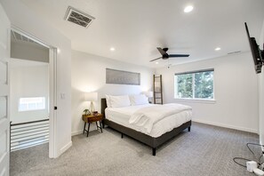 A bedroom with a bed, bedside table, lamp, ceiling fan, windows, and a ladder. - #HabitueHomes - Crossroads Retreat - Hot Tub! (Boise)