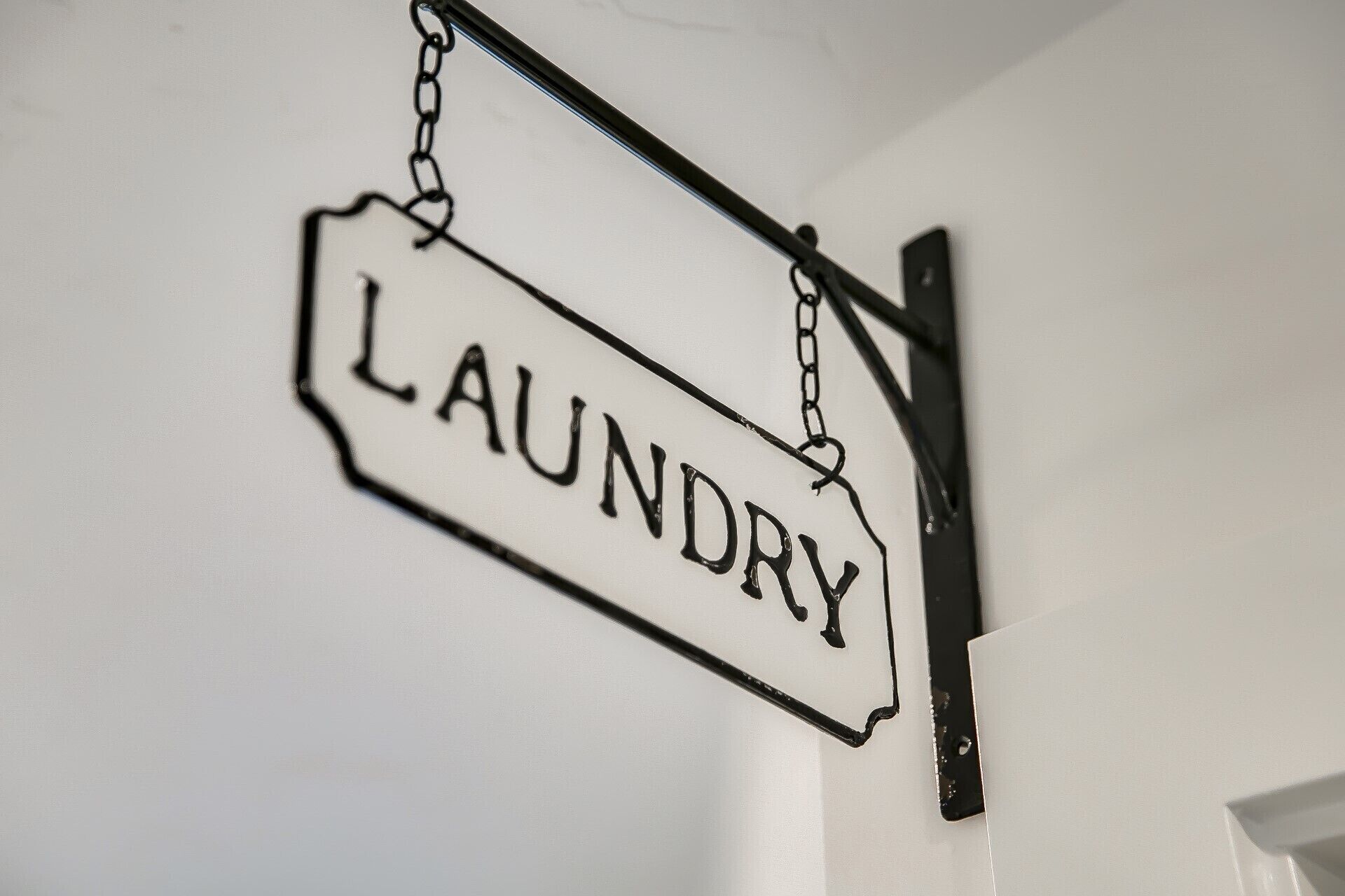 A hanging sign with the word "LAUNDRY" on a white wall.