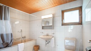 A bathroom with a bathtub, sink, toilet, and a window. - Chalet Anne Sophie (Riddes)