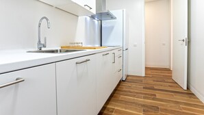 A modern kitchen with white cabinets, a stainless steel sink, and a wooden countertop. - Genteel Home San Antonio IV (Cadiz)