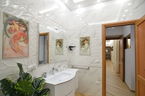 A modern bathroom with a marble sink, large mirror, and decorative wall art. - Caserta Deluxe Bis (Caserta)